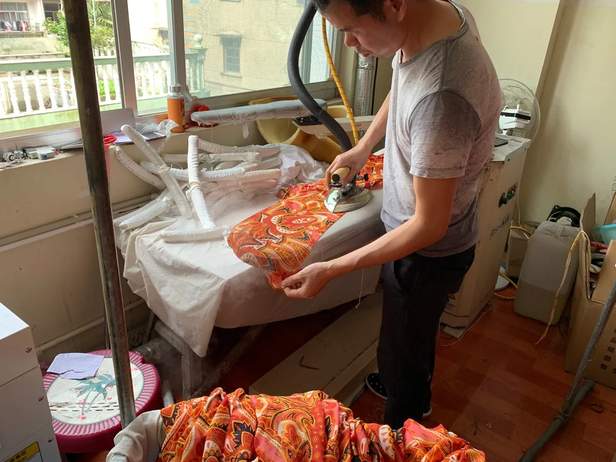 Worker steam-ironing a finished garment